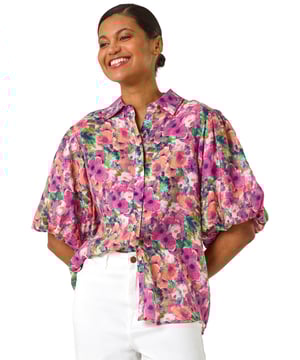Floral Print Button Through Shirt from Roman. Bring a touch of Spring Summer elegance to your wardrobe with this vibrant button blouse. The classic collar shirt style features charming button-through details and short voluminous puff sleeves for added drama, all crafted from a comfortable woven fabric adorned with a blooming floral print. Finished in a smart shirt shape, this blouse pairs perfectly with a denim jacket and jeggings for a complete look!