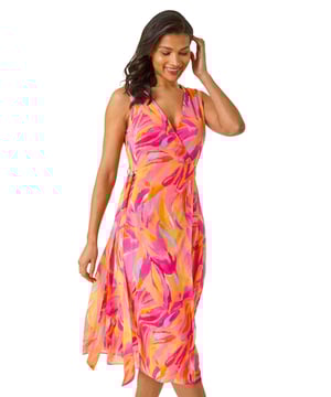 Floral Print Wrap Chiffon Midi Dress from Roman. Unleash your inner style with this stunning floral wrap dress for the Spring Summer season. Embrace its feminine charm with a v-neckline, sleeveless style and a wrap front design, all crafted from a comfortable chiffon fabric adorned with a delightful floral print. Featuring a flattering side tie detail, this dress falls elegantly at a midi length. Pair with strapped heels and a trendy bolero to complete your look.