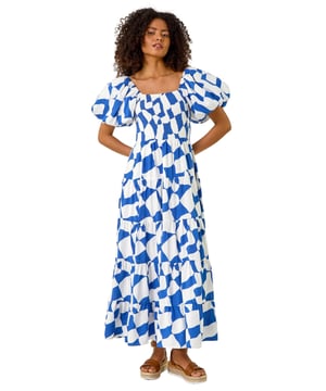 Dusk Geo Print Tiered Dress from Roman. Feel effortless this Spring Summer season with our Dusk tiered geo print dress. This trendy dress features a square neckline and playful short puff sleeves, adding a fun touch to your outfit. Cut and lined with a comfortable woven fabric, the dress boasts a flattering shirred bodice and a midi length tiered skirt, ensuring all-day comfort. Style with a denim jacket and wedge heels for the perfect look you'll love!