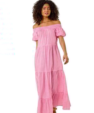Dusk Gingham Bardot Tiered Maxi Dress from Roman. Capture the essence of Spring Summer in this stunning gingham maxi dress. The feminine bardot neckline with short sleeves adds a touch of elegance to this comfortable woven fabric piece. Featuring a striking gingham print, this dress falls gracefully at a maxi length with a beautiful tiered style skirt. Pair with wedged heels for the perfect look.