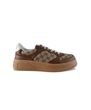 Sneakers Gucci GG in bruin leer.Gemonogrammeerd bruin GG juk op beige canvas.Label met Gucci logo op tong.Witte leren teller.Gouden logo op teller.Dikke bruine zool met logo.Beige vetersluiting.Made in Italy.