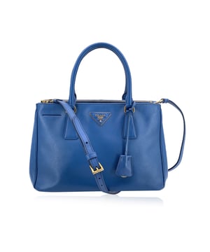 Empfohlener Verkaufspreis
Diese atemberaubende PRADA „Galleria“ Henkeltasche ist der Inbegriff von Luxus und Eleganz. Sie ist aus feinstem Saffiano-Leder in Blau gefertigt und besticht durch eine wunderschöne Mischung verschiedener Brauntöne. Das edle, strukturierte Finish ist zeitlos und vielseitig. Die strukturierte Tote-Silhouette wird durch das ikonische Leder-Triangle-Logo auf der Vorderseite ergänzt und macht sie zu einem Statement-Piece für jeden Anlass. Die Tasche wurde stilvoll und funktional gestaltet und verfügt über zwei runde Henkel für bequemen Halt sowie erweiterbare Seitenteile mit Knopfverschluss, sodass Sie die Größe ganz nach Bedarf anpassen können. Das Innere ist ebenso luxuriös wie das Äußere und vollständig mit dem charakteristischen PRADA-Stoff gefüttert. Es verfügt über ein geräumiges offenes Hauptfach, zwei Reißverschlussfächer an Vorder- und Rückseite sowie ein Reißverschlussfach und drei offene Fächer für übersichtliche Organisation. Für zusätzlichen Komfort sorgt der abnehmbare und verstellbare Schultergurt, der das Tragen als Crossbody oder in der Hand ermöglicht. Die vier Metallfüße unter der Tasche werten den Stil nicht nur auf, sondern schützen das Leder auch vor Abnutzung. Im Inneren gewährleisten das Etikett „PRADA – Made in Italy“ und ein kleines Etikett mit einer Nummer in der Innentasche die Echtheit dieses exquisiten Stücks. Mit einem Verkaufspreis von über 4.000 € ist die PRADA „Galleria“-Tasche die perfekte Investition für alle, die tadellose Handwerkskunst, Stil und Vielseitigkeit schätzen. Ob für einen Tag im Büro oder einen Abend in der Stadt, diese Tasche verspricht, jedes Ensemble aufzuwerten. Zustandsbewertung: B – SEHR GUTER ZUSTAND. Zustandsdetails: Wenig verwendet. Minimale Gebrauchsspuren an der Oberfläche der unteren Ecken. Bitte sehen Sie sich die Fotos sorgfältig an und fragen Sie nach, wenn Sie weitere Details benötigen oder Fragen haben. Maße (cm): Tiefe: 12,7 Höhe: 20,3 Länge: 30,5 Weitere Details: Staubbeutel? Nein Schlüssel? Nein Box? Nein Maße: Breite: 127 mm Länge: 305 mm Höhe: 203 mm