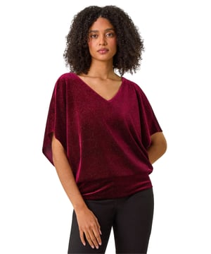 Glitter Velvet Banded Hem Stretch Top from Roman. Elevate your Autumn Winter wardrobe with our stunning velvet top. The flattering v-neckline leads into a modern bar back detail, while the elasticated band hem creates a tunic shape. Crafted from a textured velvet fabric with a subtle shimmer, this top is perfect for day wear with a touch of glamour. Style with jeggings and ankle boots for a trendy fall look.