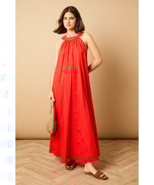 Elegant halterneck design with delicate ruffle trim detail
        Flowing maxi length for graceful movement
        Relaxed smock silhouette offering effortless comfort
        Lightweight cotton voile fabric perfect for warmer days
        Tie-back fastening for an adjustable, secure fit
    
    This breezy halterneck maxi dress captures the essence of carefree summer style with its billowing smock silhouette. The soft ruffle trim around the neckline adds a touch of feminine charm, whilst the flowing fabric creates a beautifully relaxed drape that moves gracefully with every step. Style with flat sandals as seen on our model for daytime outings, or dress up with espadrille wedges and statement earrings for garden parties and alfresco dining. The versatile design makes it ideal for family gatherings, weekend brunches or holiday packing - simply throw on with a denim jacket and crossbody bag for an effortlessly chic look that transitions seamlessly from day to evening. The lightweight fabric ensures all-day comfort, whether you're strolling along the beach or enjoying a casual lunch with friends.