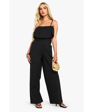 Feminine ruffle overlay detail across the bodice for added dimension
        Adjustable spaghetti straps for a customised fit
        Wide-leg silhouette offering comfort and effortless movement
        Flattering cinched waist design to enhance your natural shape
        Versatile cotton-mix fabric suitable for day-to-night styling
    
    This chic Boohoo jumpsuit combines casual comfort with fashion-forward design. The delicate ruffle detail adds a playful touch to the strappy neckline, while the wide-leg cut creates a relaxed yet sophisticated silhouette. Style with flat sandals and a woven clutch, as shown, for daytime gatherings or family brunches. For evening socials, swap your flats for block heels and add statement earrings. The cotton-mix fabric offers breathability for all-day wear, making this piece perfect for summer festivals, garden parties or casual weekend outings. The simple yet striking design works beautifully with minimal accessories - try a dainty bracelet or layered necklaces to complete your look without overwhelming the jumpsuit's elegant simplicity.