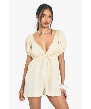 Charming cotton poplin playsuit with flattering sweetheart neckline
        Romantic puff sleeves add a touch of feminine flair
        Elasticated back design ensures comfortable all-day wear
        Cinched waist creates a figure-enhancing silhouette
        Open back detail adds a subtle touch of allure
    
    This delightful cotton playsuit from Boohoo captures the essence of carefree summer style with its charming puff sleeves and sweet sweetheart neckline. Perfect for casual outings, the lightweight cotton poplin fabric offers breathable comfort whilst the elasticated back ensures a snug yet comfortable fit. Style with pearl accessories as shown for a touch of elegance, or dress down with white trainers and a crossbody bag for daytime adventures. The versatile design makes it ideal for family barbecues, weekend brunches or casual garden parties. For cooler evenings, layer with an oversized denim jacket and swap your flats for ankle boots to transition seamlessly into night. The playful silhouette strikes the perfect balance between comfort and style, making it a must-have addition to your casual wardrobe.