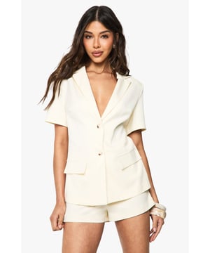 Structured woven fabric with subtle textured finish for added dimension
        Sophisticated V-neckline with tailored collar detail
        Short sleeves with clean-cut edges for a modern silhouette
        Functional front button fastening with two practical patch pockets
        Coordinated shorts with a flattering high-waisted design
    
    This structured playsuit from Boohoo delivers a contemporary twist on classic tailoring, perfect for making a statement on your next night out. The blazer-inspired top half creates a polished look whilst the shorts offer comfort and freedom of movement. Style with strappy heels and statement bangles as shown for drinks with the girls, or dress it up with metallic accessories and a sleek clutch for more upscale venues. The versatile design transitions effortlessly from sunset cocktails to late-night dancing. For cooler evenings, layer with a lightweight jacket or wear with sheer tights to extend its wearability. The clean lines and tailored silhouette create a refined yet fashion-forward ensemble that's sure to turn heads whilst maintaining that effortless vibe Boohoo is known for.