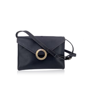 VINTAGE, RRP AS NEW
Step into the quiet allure of French sophistication with this Celine black leather Ring convertible shoulder bag - a piece that whispers luxury with every detail. Crafted in supple black leather, its silhouette is gracefully understated, allowing the gleaming gold-tone signature ring on the front flap to take center stage - a subtle yet iconic mark of Celine's refined design language.  The flap secures with a magnetic button closure, opening to reveal a smooth black leather-lined interior, complete with a single side zip pocket for your small essentials. Whether slung over the shoulder with its adjustable, removable strap or held as a clutch, this versatile piece moves effortlessly from day to night, café to cocktail hour.  Proudly bearing the Celine Paris - Made in Italy tag inside, this bag carries not just style, but a legacy of craftsmanship. A classic reimagined for the modern collector, it's the kind of piece that doesn't just accessorize an outfit - it tells a story.  Condition Rating: B - VERY GOOD CONDITIONCondition Details: Gently used. Some light scratches on leather due to normal use. Some loss of gilding on the front hardware. Please check the photos carefully and ask if you need to know more details or if you have any doubts.Measurements (cm):Depth: 3.8Height: 17.8Length: 24.1Other Details: Dustbag? NoKeys? NoBox? No Measurments:  width: 38 mm length: 241 mm height: 178 mm