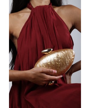 Make a statement with the ocean-inspired Benna Marble Acrylic Clutch In Gold, designed to turn heads at any special event. Its sculpted silhouette and glossy marbled finish evoke luxurious, artistic charm. Finished with a sleek gold-tone clasp, this compact clutch carries your essentials in standout style. Key Features: • Material: High-gloss marbled acrylic • Dimensions: Approximately 19cm (L) x 11cm (H) x 5cm (W) • Fastening: Gold-tone twist clasp closure • Detail: Unique curved design with swirling marble effect for a luxe finish