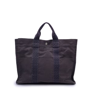 VINTAGE, RRP AS NEW
Hermes Canvas Herline Her Line Yale MM Tote Bag in grey and black colors. Made of a durable canvas. The tote has durable strap handles of a patterned Hermes H canvas. 3 open pockets on the front. Composition; 69% Polyamide, 31% Polyester. 3 snap button closure + Double zipper closure on top. Canvas internal lining. 1 side open pocket inside. Made in France.  In the rhythm of timeless design and understated luxury, the Hermès Herline Yale MM Tote Bag emerges as a quiet icon of the early 2000s-when minimalism met functionality in the most Parisian of ways. Rendered in a durable grey and black canvas, this tote is both utilitarian and elegant, speaking to those who appreciate design that whispers rather than shouts.  Its name, Herline, nods to its heritage: a line born of everyday elegance, while Yale MM hints at its medium, versatile size-perfect for city errands, studio days, or a quiet weekend escape. The bag's exterior boasts three open front pockets, stitched seamlessly into the patterned Hermès 'H' canvas handles-signature straps that are as durable as they are iconic.  Crafted from a blend of 69% polyamide and 31% polyester, this piece is made to withstand both time and trend. A triple snap button and double zip closure ensure your essentials stay secure, while inside, a simple canvas lining and a single side pocket maintain the clean, practical interior.  Made in France, this Herline Yale MM is more than just a tote-it's a chapter in the Hermès story, waiting to become part of yours. Condition Rating: A - EXCELLENTCondition Details: Gently used. A couple of small faded stains on the exterior. A couple of faded stains on the internal lining. Some wear of use on bottom corners. Please check the photos carefully and ask if you need to know more details or if you have any doubts.Measurements (cm):Depth: 10.2Height: 31.8Length: 41.9Other Details: Dustbag? NoKeys? NoBox? No Measurments:  width: 102 mm length: 419 mm height: 318 mm