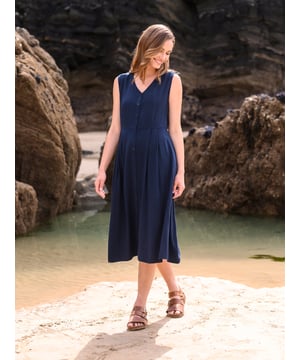 This flattering dress features a gently fitted bodice to the waist, a V neckline, and a flared skirt. The full-length button-through detail is fastened with Corozo nut buttons, while two side pockets offer practicality. Crafted from a smooth, soft and drapey woven material, this dress combines simplicity and comfort seamlessly.