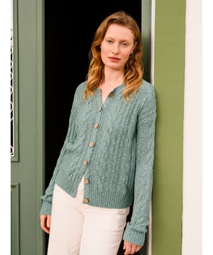 This cardigan has a classic cable-knit pattern with a relaxed, drop-shoulder shape, finished with natural coconut buttons. The cotton-linen blend lends an airy feel, while the crew neckline and boxy fit create an easy, everyday layer.