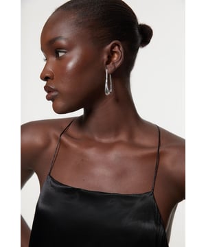 These sophisticated Karen Millen drop hoop earrings offer the perfect balance between classic elegance and modern design. The elongated silhouette creates a flattering frame for your face while adding a touch of refinement to any ensemble. Style with a crisp white shirt and tailored blazer for corporate events, or pair with an evening gown for formal occasions such as weddings and galas. Their versatility allows them to transition effortlessly from daytime sophistication to evening glamour, making them an indispensable addition to your jewellery collection.  Drop hoop design Sleek metal finish Lightweight construction Secure fastening mechanism