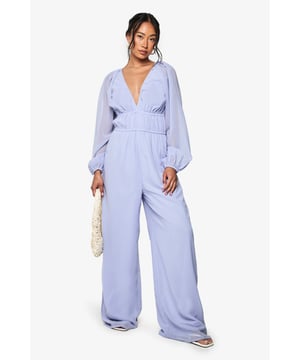 Elegant chiffon jumpsuit featuring a plunging V-neckline for a striking silhouette
        Ruched waistband detail creates a flattering, defined waist
        Dramatic wide-leg design offers comfortable movement and a fashion-forward look
        Billowing long sleeves with gathered cuffs add romantic flair
        Flowing fabric drapes beautifully for an effortlessly chic appearance
    
    Make a statement at your next night out in this show-stopping wide-leg jumpsuit. The plunging V-neckline creates an alluring focal point, whilst the ruched waistband cinches you in at just the right spot for a figure-enhancing effect. The billowing sleeves and flowing wide legs create a beautifully balanced silhouette that moves gracefully as you do. Style with strappy heels and a woven clutch, as shown, for drinks with the girls, or dress it up with statement earrings and metallic accessories for special occasions. This versatile Boohoo piece transitions seamlessly from cocktail bars to dance floors, ensuring you'll stand out for all the right reasons. Perfect for those who want to combine comfort with head-turning style for their evening adventures.