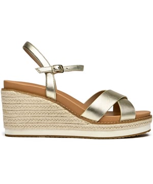 The Cole Haan Silvee transforms the classic espadrille with luxurious gold nubuck and a statement 9cm heel that elevates any summer look. Its rope-edged sole maintains that quintessential Mediterranean charm while the cushioned insole ensures all-day comfort. The secure buckle closure and premium rubber-rope construction make these sandals as practical as they are stunning, perfect for rooftop dinners or seaside strolls.