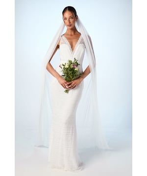 Elegant plunge neckline with delicate lace detailing for a romantic touch
        Figure-flattering fishtail silhouette that gracefully contours the body
        Stunning open back design creating a captivating rear view
        Lightweight chiffon fabric offering comfortable movement throughout your special day
        Floor-length design with subtle train detail for a dramatic entrance
    
    Make a breathtaking statement on your wedding day with this enchanting boho fishtail gown. The sophisticated plunge neckline frames your dcolletage beautifully, whilst the expertly crafted silhouette skims your curves before gently flaring at the knee for that coveted mermaid effect. The delicate lace detailing adds texture and dimension, creating visual interest without overwhelming the clean lines of the dress. Perfect for both traditional ceremonies and outdoor celebrations, this gown can be styled with a cathedral-length veil as shown for classic bridal elegance, or with fresh floral accessories for a more bohemian aesthetic. Complete your bridal ensemble with minimal jewellery to maintain focus on the gown's exquisite design, and pair with strappy heels for added height and poise as you glide down the aisle.