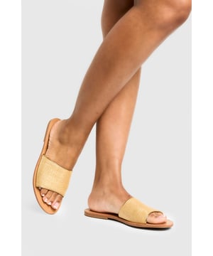 Textured bast-style slide sandals with a single wide strap design
        Flat heel measuring between 0-2cm for all-day comfort
        Open toe silhouette perfect for showcasing pedicures
        Slip-on style for effortless wear
        Versatile neutral tone that complements any summer outfit
    
    These minimalist bast-style sandals from Boohoo combine simplicity with versatility for your warm-weather wardrobe. The understated design features a comfortable flat sole that's ideal for city exploring or beachside strolls. Style them with cropped linen trousers and an oversized shirt for casual daytime outings, or pair with a flowing maxi dress for family gatherings and garden parties. The neutral tone works brilliantly with bold prints and patterns, making these sandals a true wardrobe staple. For festival season, match them with denim shorts and a graphic tee, adding layered jewellery for a touch of bohemian flair. Their lightweight construction makes them perfect for packing in your holiday suitcase, whilst the durable sole ensures they'll remain a favourite throughout the summer months.