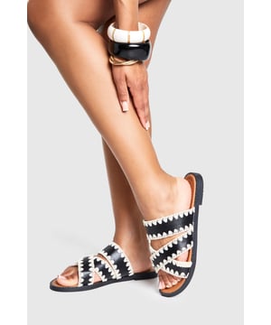 Striking contrast cross-over design with distinctive zig-zag stitching detail
        Comfortable flat heel measuring between 0-2cm for all-day wear
        Open-toe silhouette with dual cross-over straps for a secure fit
        Durable PU construction with textured sole for added grip
        Slip-on style for effortless wearing and removal
    
    These eye-catching cross-over sandals bring a touch of artisanal flair to your casual wardrobe. The distinctive contrast stitching creates a bold visual statement whilst maintaining a relaxed vibe perfect for summer styling. Pair with cropped linen trousers and an oversized shirt for daytime outings, or team with a flowing maxi dress for garden parties and family gatherings. The flat design ensures comfort for extended wear, making these sandals ideal for city explorations or beachside strolls. Their versatile aesthetic works brilliantly with both neutral and vibrant ensembles, allowing you to customise your look according to the occasion. A statement bangle, as shown on the model, completes the look with a contemporary twist - the perfect finishing touch for these Boohoo sandals that balance style and practicality with effortless charm.