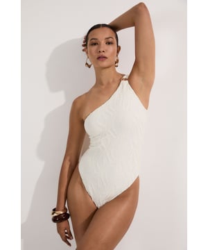 Make a statement poolside in this Karen Millen textured swimsuit that combines sophistication with modern design elements. The asymmetric one-shoulder neckline creates a dramatic focal point, enhanced by the luxe metallic hardware detail. The distinctive cut-out adds intrigue while maintaining a flattering shape. The textured fabric offers visual interest and dimension that catches the light beautifully as you move. Style with oversized sunglasses and gold-toned jewellery for lounging by the pool, or pair with a flowing maxi skirt and sandals for beachside dining. This versatile piece transitions effortlessly from daytime swimming to sunset cocktails when worn as a bodysuit with wide-leg trousers. Perfect for your summer holiday wardrobe, this swimsuit delivers both style and substance for confident beach days.   Striking one-shoulder design with metallic hardware detail Textured fabric creates a sophisticated dimensional effect Strategic cut-out detail adds a contemporary twist Fully lined for comfort and confidence Sculpting fit that flatters the silhouette