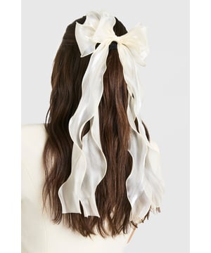 Oversized bow design for a statement look
        Sheer organza fabric creates an ethereal effect
        Long, flowing ribbons for added movement
        Secure metal clip for easy attachment
        Versatile accessory suitable for various hairstyles
    
    Add a touch of whimsy to your ensemble with this enchanting organza hair bow. The oversized design commands attention, while the sheer fabric lends an air of delicate sophistication. Perfect for casual outings or family gatherings, this accessory effortlessly elevates any look. Style it with loose waves for a romantic vibe, or use it to accent a sleek ponytail for a more polished appearance. The long, flowing ribbons create a captivating effect as you move, making it ideal for those who love to make a subtle yet striking impression. Whether you're headed to a picnic in the park or a laid-back brunch with friends, this versatile hair bow is sure to become a go-to piece in your accessory collection.