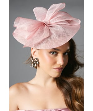 Striking layered bow design creating a dramatic silhouette
        Lightweight Abaca material for comfortable all-day wear
        Secure headband fitting that sits elegantly on one side
        Textured finish that catches the light beautifully
        One size design suitable for various hairstyles
    
    Make a sophisticated statement at your next special occasion with this exquisitely crafted fascinator. The layered bow detail creates a sense of movement and dimension, whilst the angled positioning offers a contemporary twist on traditional millinery. Style with an elegant updo to showcase the fascinator's intricate design, or wear with loose waves for a more relaxed yet refined look. Perfect for weddings, the races or garden parties, this headpiece pairs wonderfully with a tailored dress or a chic coordinated ensemble. For maximum impact, complement with statement earrings and a clutch bag in harmonising tones. This versatile fascinator will transform any formal outfit into a truly memorable ensemble, ensuring you stand out for all the right reasons.