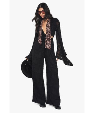 Dramatic wide sleeves with flared cuffs for a statement silhouette
        Plunge neckline creates a bold, sophisticated focal point
        Textured chiffon fabric adds dimension and visual interest
        Wide-leg design offers comfort and elegant movement
        Cinched waist with ring detail creates a flattering hourglass shape
    
    Command attention at your next formal occasion in this striking wide-sleeve jumpsuit from Boohoo. The daring plunge neckline balances beautifully with the flowing wide-leg silhouette, creating a look that's both dramatic and refined. Style with statement earrings and a sleek clutch as shown, or add your own flair with metallic accessories. The textured chiffon fabric catches the light beautifully as you move, making it perfect for weddings, cocktail parties, or evening receptions. For cooler evenings, layer with a tailored blazer without compromising on impact. Complete the ensemble with platform heels to enhance the jumpsuit's lengthening effect - a versatile piece that transitions effortlessly from day ceremonies to evening celebrations with just a change of accessories.