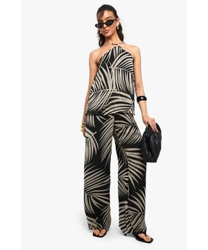 Striking palm print chiffon jumpsuit with flowing wide-leg silhouette
        Distinctive asymmetric neckline with halter-style tie detail
        Lightweight, floaty fabric that moves beautifully with every step
        Relaxed fit through the bodice for effortless comfort
        Floor-skimming length perfect for showcasing statement footwear
    
    Make a bold statement in this eye-catching chiffon jumpsuit from Boohoo. The dramatic palm print creates visual interest whilst the asymmetric neckline adds a contemporary twist to this casual piece. Style with flat sandals and oversized sunglasses for daytime gatherings, or dress it up with chunky bangles and a quilted handbag as seen on our model for evening drinks. The wide-leg design offers both comfort and drama, creating a flattering silhouette that's perfect for warm-weather socialising. This versatile jumpsuit transitions seamlessly from family barbecues to beachside strolls, and can be layered with a cropped denim jacket when the temperature drops. Pair with simple accessories to let the striking print take centre stage.