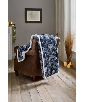 Step into a storybook forest with the Deyongs Woodland Folk Throw, available in enchanting Navy or deep Green. This intricately illustrated design features graceful deer nestled among foliage, acorns, and forest flora, creating a cosy woodland scene that brings nature indoors. The front is made from soft 220gsm printed flannel, while the reverse is lined with plush 200gsm sherpa for the ultimate in warmth and comfort. Sized at 140x180cm and crafted from easy-care 100% polyester, this t