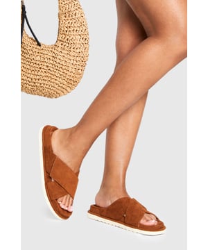 Faux suede cross strap design for a contemporary summer look
        Comfortable footbed with cushioned insole for all-day wear
        Flat heel measuring between 0-2cm for easy walking
        Lightweight white sole creating a modern contrast effect
        Slip-on style for effortless convenience
    
    These cross strap footbed sliders from Boohoo combine comfort and style for your casual summer wardrobe. The distinctive cross strap design creates visual interest whilst maintaining the relaxed vibe essential for warm-weather dressing. Pair with cropped linen trousers and an oversized shirt for a sophisticated daytime look, or team with a floaty midi dress for garden parties and barbecues. The contrast white sole adds a contemporary touch to these versatile sliders, making them perfect for beach holidays, city breaks or simply lounging in the garden. Their slip-on nature means they're ideal for quick outfit changes, whilst the cushioned footbed ensures comfort for sightseeing or casual strolls. A summer essential that works beautifully with both casual and slightly dressier daytime ensembles.
