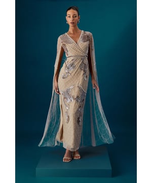 Exquisite hand-stitched embellishments create a dazzling geometric pattern across the entire dress
        Dramatic cape sleeves flow elegantly from shoulders to floor, creating a regal silhouette
        Flattering V-neckline frames the dcolletage beautifully
        Figure-enhancing wrapped bodice detail accentuates the waistline
        Floor-sweeping maxi length with subtle front split for graceful movement
    
    This showstopping Coast maxi dress commands attention with its lavish hand-stitched embellishments and ethereal cape sleeves. The wrapped V-neckline bodice creates a flattering silhouette whilst the intricate beadwork catches the light with every movement. Style with delicate strappy heels as seen on our model and a sleek updo to showcase the dress's exquisite detailing. Perfect for weddings and formal occasions where making an impression matters-this piece transitions beautifully from day ceremonies to evening receptions. For cooler evenings, drape a lightweight pashmina over your shoulders without detracting from the cape detail. Complete your ensemble with minimal jewellery; the dress's ornate embellishments provide all the sparkle you need for your special occasion.