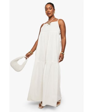 Tiered maxi design with flowing silhouette for effortless movement
        Distinctive strappy neckline with decorative front detail for added interest
        Lightweight linen-look fabric perfect for warm-weather comfort
        Relaxed fit with generous cut through body for all-day ease
        Versatile floor-length style suitable for various casual occasions
    
    This breezy tiered maxi dress captures carefree summer style with its flowing silhouette and distinctive strappy neckline. The decorative front detail adds a touch of bohemian charm, while the lightweight linen-look fabric ensures comfort during warmer days. Style with flat sandals and a mini handbag as shown for daytime gatherings, or customise with layered gold jewellery and espadrilles for alfresco dining. The relaxed fit makes this Boohoo piece ideal for family barbecues, beach outings, or casual weekend brunches. Its neutral versatility allows for endless accessorising options - try adding a denim jacket for cooler evenings or a wide-brimmed hat for garden parties. This plus-size dress combines effortless style with practical comfort for your everyday summer wardrobe.