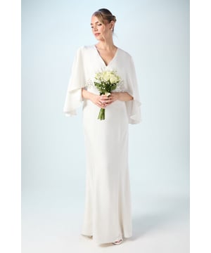 Elegant V neckline frames the dcolletage beautifully for a timeless bridal silhouette
        Dramatic batwing sleeves create a cape-like effect, adding movement and sophistication
        Sleek column silhouette with a floor-sweeping length for a statuesque appearance
        Luxurious satin fabric catches the light with a subtle sheen for that special day
        Delicate back detail with a refined keyhole closure for an elegant finishing touch
    
    Make a graceful statement on your wedding day with this sophisticated satin gown from Coast. The flowing batwing sleeves create a dramatic silhouette whilst maintaining an air of refined elegance, perfect for the modern bride who values both comfort and style. The clean lines of the column skirt complement the architectural upper design, creating balance and poise as you walk down the aisle. Style with minimal jewellery to let the dress command attention-perhaps pearl drop earrings and a simple bracelet. For a complete bridal look, carry a bouquet of fresh blooms as shown and wear your hair in a sleek updo to showcase the beautiful neckline. This versatile design would suit both traditional church ceremonies and contemporary venue celebrations, making it a truly memorable choice for your special day.