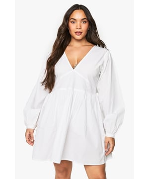 Flattering V-neckline with smocked bodice detail for a comfortable fit
        Voluminous blouson sleeves that create a romantic silhouette
        Open back design with delicate tie fastening for an unexpected twist
        Relaxed A-line shape with gathered skirt for effortless movement
        Versatile mini length perfect for day-to-night styling
    
    This charming cotton smock dress combines comfort with contemporary style. The smocked bodice creates a flattering fit whilst the blouson sleeves add a touch of drama to this otherwise understated piece. The open back with tie detail offers a playful element that's perfect for warmer days. Style with white trainers and a mini handbag for casual daytime outings, as shown on our model. For family gatherings or brunch dates, pair with delicate jewellery and strappy sandals. The relaxed silhouette makes this Boohoo dress a versatile addition to your wardrobe that works beautifully for garden parties, weekend shopping trips, or casual meet-ups with friends. The easy-to-wear design ensures you'll reach for this dress time and again throughout the seasons.