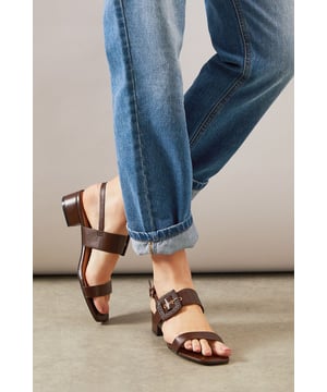 Stylish slingback design with adjustable buckle fastening for a secure fit
        Distinctive raffia-textured buckle detail adds a touch of artisanal flair
        Comfortable low block heel measuring between 2.5-4.5cm for all-day wearability
        Clean-lined silhouette with minimalist strap detailing for versatile styling
        Faux leather construction offers a sophisticated finish with practical durability
    
    The Raelynn sandals from Wallis present the perfect balance of comfort and sophistication for your daytime wardrobe. The thoughtfully designed low block heel provides stability whilst the slingback style with its distinctive raffia buckle detail adds a touch of textural interest to any ensemble. These versatile sandals pair beautifully with flowing midi dresses as shown, but work equally well with tailored trousers or casual denim. Ideal for garden parties, weekend brunches or casual family gatherings where you want to look polished without sacrificing comfort. The neutral tone makes these an excellent investment piece that will complement numerous outfits throughout the warmer months. For a coordinated daytime look, match with a structured handbag and delicate jewellery to showcase your sophisticated yet relaxed style.