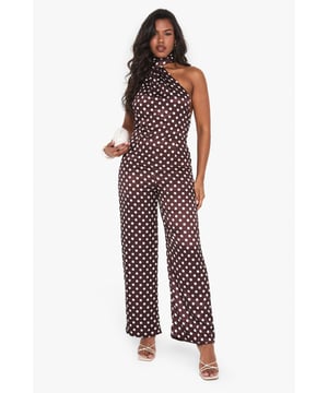 Striking polka dot satin jumpsuit with elegant high neck design
        Sophisticated scarf detail adds dramatic flair to the neckline
        Flattering wide-leg silhouette for effortless movement
        Statement open back design for head-turning appeal
        Perfect one-piece solution for special occasions with minimal styling required
    
    Make a striking entrance at your next formal event in this captivating polka dot satin jumpsuit from Boohoo. The distinctive high neck with scarf detail creates a sophisticated focal point, while the open back adds a touch of allure. The wide-leg cut offers both comfort and elegance, creating a flowing silhouette that moves beautifully as you walk. Style with metallic strappy heels as shown for a refined evening look, and add statement earrings to complement the neckline. This versatile piece transitions seamlessly from weddings to graduation ceremonies and race day events. For cooler evenings, layer with a tailored blazer or delicate wrap to maintain the jumpsuit's elegant profile whilst adding warmth.
