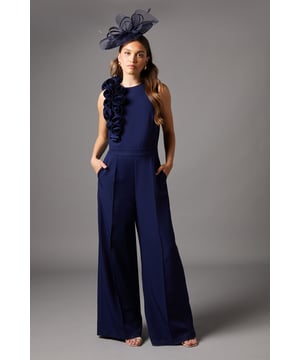Striking corsage detail adorning the shoulder
        Elegant round neckline for a sophisticated look
        Pleated wide-leg trousers for a flowing silhouette
        Sleeveless design perfect for warm-weather events
        Flattering regular fit suitable for various body types
    
    Make a lasting impression at your next formal occasion with this stunning corsage detail pleated jumpsuit from Coast. The eye-catching floral embellishment cascading down one shoulder adds a touch of drama and femininity to this already elegant piece. The wide-leg trousers create a graceful, flowing silhouette that elongates your frame, while the sleek, fitted bodice accentuates your waistline. Style this versatile jumpsuit with strappy metallic heels and a clutch bag for a sophisticated ensemble perfect for weddings, race days, or evening galas. For a more understated look, pair it with nude pumps and delicate jewellery. This jumpsuit is a true statement piece that combines comfort and style, ensuring you'll stand out for all the right reasons at any formal event.