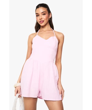 Textured cheesecloth fabric adds subtle dimension and visual interest
        Flattering scoop neckline frames the dcolletage beautifully
        Halterneck design with tie fastening for adjustable comfort
        Relaxed fit through the shorts for effortless movement
        Open back detail creates a striking silhouette
    
    This breezy Strukturierter Playsuit from Boohoo combines comfort with carefree style for your warm-weather wardrobe. The lightweight cheesecloth texture gives this piece a relaxed, holiday-ready feel whilst the halterneck design showcases shoulders and creates a feminine shape. Style with flat sandals and a woven tote bag as shown for daytime outings, or customise your look with layered bangles and oversized sunglasses for casual gatherings. The playful silhouette works brilliantly for garden parties, beachside lunches or family barbecues. For cooler evenings, throw on a denim jacket and switch to espadrilles to maintain that effortless summer aesthetic. This versatile playsuit transitions seamlessly from day to evening whilst keeping you comfortable throughout.