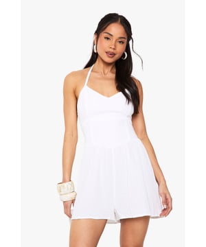 Textured cheesecloth fabric adds subtle dimension and breathability to this effortless playsuit
        Flattering scoop neckline frames the dcolletage beautifully
        Halterneck design with tie fastening offers adjustable support
        Relaxed fit through the shorts creates a comfortable, easy-to-wear silhouette
        Lightweight construction makes it perfect for warm-weather styling
    
    This breezy cheesecloth playsuit from Boohoo delivers carefree style with a feminine touch. The halterneck design and scoop neckline create a flattering frame for your shoulders and collarbone, whilst the relaxed shorts provide comfort without sacrificing style. Style with chunky bangles and hoop earrings as shown for a laid-back daytime look, or swap the flat sandals for espadrille wedges to transition into evening. Perfect for family barbecues, beach outings, or casual coffee dates, this versatile playsuit works brilliantly with a denim jacket for cooler evenings. Add a crossbody bag like the model's woven accessory to keep your essentials close whilst maintaining the playsuit's effortless aesthetic. A true summer wardrobe hero that combines comfort and style.