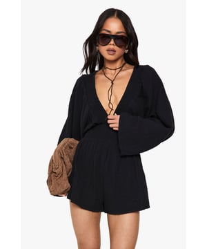 Crafted from lightweight cheesecloth fabric for ultimate comfort
        Striking plunge neckline creates a bold statement look
        Relaxed wide sleeves offer effortless movement and style
        Elasticated waist provides a flattering silhouette
        Versatile short length perfect for warmer weather
    
    This eye-catching playsuit from Boohoo combines comfort with head-turning style. The dramatic plunge neckline creates a striking focal point, while the cheesecloth fabric ensures a light, breathable feel against the skin. Style with knee-high boots and a shoulder bag for daytime casual events as shown, or switch to chunky trainers and a denim jacket for family gatherings. The relaxed fit with elasticated waist makes this an easy-to-wear option that requires minimal styling effort. For cooler evenings, layer with an oversized cardigan and add statement jewellery to enhance the neckline detail. This versatile piece transitions effortlessly from day to night, making it a must-have addition to your casual wardrobe.