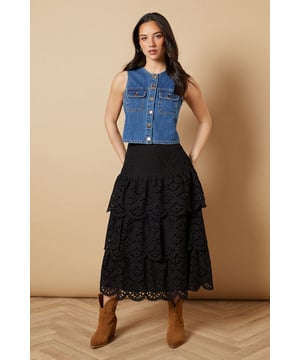 Intricate broderie anglaise detailing with floral eyelet pattern throughout
        Elegant tiered design creates beautiful movement and dimension
        Midi length falls gracefully below the knee for a feminine silhouette
        Scalloped hem adds a delicate finishing touch to each tier
        High-waisted fit accentuates the natural waistline
    
    This charming broderie tiered midi skirt from Oasis combines timeless femininity with contemporary styling. The delicate eyelet pattern creates a romantic texture that catches the light beautifully as you move, while the tiered construction adds playful volume and flow. Style with a denim waistcoat as shown for a balanced casual look, or pair with a fitted blouse for garden parties and family gatherings. The versatile midi length works wonderfully with both ankle boots for cooler days or flat sandals when the temperature rises. This skirt transitions effortlessly from daytime outings to casual evening events - simply switch your accessories to refresh your look. The high-waisted design flatters your figure whilst providing comfort for all-day wear.