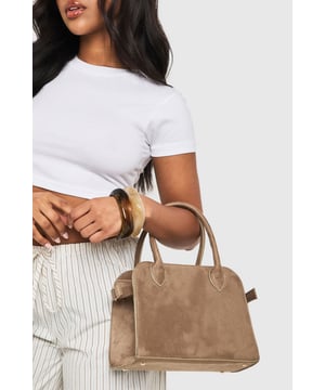 Faux suede bowling bag with structured silhouette for a timeless look
        Dual top handles with elegant curved design for comfortable carrying
        Detachable shoulder strap offering versatile wearing options
        Gold-tone hardware accents adding a touch of sophistication
        Spacious interior providing ample room for daily essentials
    
    The Wildleder Bowling-Tasche brings classic charm to your accessory collection with its sophisticated structured design and soft faux suede finish. Perfect for casual outings, this versatile bag pairs beautifully with both relaxed and smart-casual ensembles. Style with striped trousers and a fitted tee for daytime coffee dates, or complement weekend wear with jeans and an oversized jumper. The practical size makes it ideal for family gatherings and shopping trips, while the detachable strap allows you to switch between handheld elegance and hands-free convenience. This Boohoo staple works wonderfully for casual events where you need to carry more than just the basics without compromising on style. The neutral tone ensures it will coordinate seamlessly with your existing wardrobe for maximum versatility.