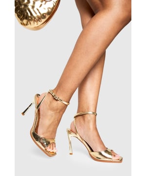 Striking metallic-effect finish that catches the light beautifully
        Elegant ankle strap with adjustable buckle fastening for secure fit
        Sleek 8cm stiletto heel adds height and sophistication
        Minimalist open-toe design showcases pedicures perfectly
        Versatile silhouette works for both formal events and night-out looks
    
    These show-stopping metallic heels are the ultimate statement piece for your evening wardrobe. The clean, modern lines and eye-catching finish create a luxurious aesthetic that commands attention without overwhelming your outfit. Style them with a little black dress for classic nightclub glamour, or pair with tailored trousers and a silky camisole when heading out for cocktails. The practical ankle strap ensures comfort and stability throughout the night, while the 8cm heel provides the perfect balance of height and wearability. These versatile heels transition effortlessly from summer weddings to festive celebrations, making them a year-round essential for the fashion-forward woman who values both style and practicality. A true Boohoo classic that delivers maximum impact with minimal effort.