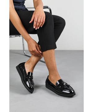Add sleek sophistication to your shoe collection with these Lucy Tasseled Loafers. Featuring a glossy finish and classic tassel detail, they blend timeless design with a modern chunky sole. The cushioned insole ensures comfort for all-day wear, making them perfect for work, weekends, or smart-casual outings. Effortlessly stylish and easy to pair with any outfit. Key Features: • Material: Patent faux leather upper with soft cushioned lining • Design: Traditional loafer silhouette with tassel detail and elevated sole • Closure: Easy slip-on style