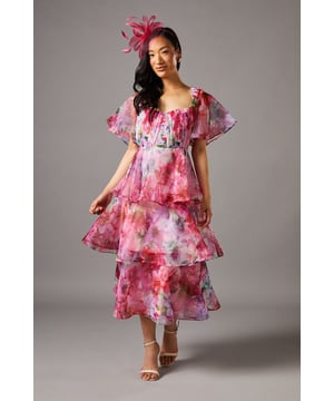Stunning organza tiered dress with dramatic three-tier skirt design for captivating movement
        Elegant sweetheart neckline complemented by delicate flutter sleeves
        Pleated bodice detail adding texture and visual interest
        Midi-length silhouette falling gracefully to mid-calf
        Flattering fitted waist creating a feminine silhouette
    
    Make a statement at your next special occasion with this enchanting organza tiered dress from Coast. The ethereal, lightweight fabric creates a dreamy silhouette whilst the sweetheart neckline frames your dcolletage beautifully. The three-tier design adds dramatic volume and movement, perfect for garden parties or race day events. Style with strappy heels as seen on our model, and add a coordinating fascinator for classic British occasion wear. For cooler evenings, layer with a lightweight pashmina. This versatile piece transitions effortlessly from daytime celebrations to evening soires-simply switch your accessories from pearl earrings to something more striking for after-dark glamour. The midi length offers both sophistication and practicality, ensuring you remain elegant throughout your special event.