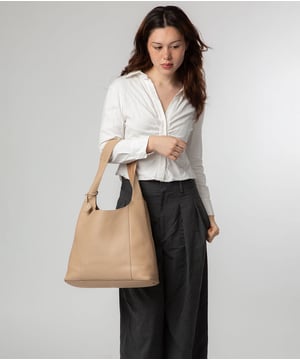 The 'Renata' shoulder bag from NiNa Amora elevates this design with the natural leather exeterior with a soft to the touch pebble grain finish. A open-top design gives it a relaxed slouchy look and conceals the spacious main compartment. This is comnplemented by a zipped pocket on the lined interior for a robust finish. A chunky single handle adorns this style and makes it comfortable to wear all day long. This is all finished with the NiNa Amora X logo embossed in stunning silver foil on the front and hanging charm for a luxurious finishing touch.