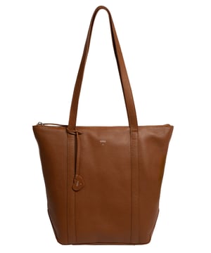 Handcrafted from natural leather with a soft to the touch pebble grain finish, the 'Lara' tote bag from NiNa Amora is a sophsitcated take on this classic design. A spacious lined main compartment is secured with a zip-over top which opens to reveal additional storage in the form of zipped and slip pockets, perfect for maintaining an organised accessory. Dual slim leather handles adorn this style with a drop length of 30cm. This style is finished with silver metal fittings and zips alongside the NiNa Amora logo embossed in silver foil on front and hanging charm; a luxurious finishing touch.
