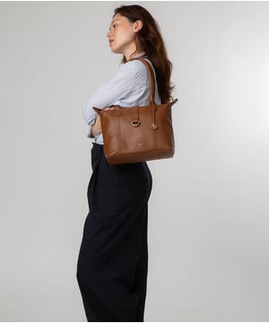 As part of the NiNa Amora brand, the'Luana' tote bag is inspired by our designer's daughter and all about elevating classic designs with high quality leather craftsmanship. A zip-over top secures the spacious central compartment alongside an attractive leather strap with silver metal fitting which folds over. On the interior, you find a lined compartment with a zipped and slip pocket which offers the perfect space for your keys, phone and any other essentials. Dual rounded erogonomic handles adorn this style with a drop length of 25cm. This accessory is elevated with silver metal fittings and zips which complement the silver foil embossed NiNa Amora X logo that add a luxrious and sophisticated finishing touch.
