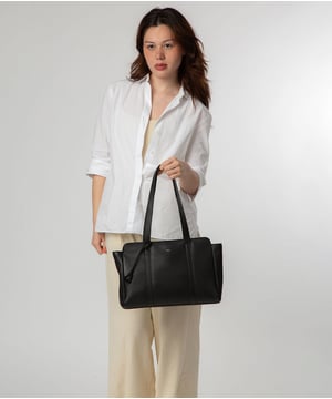 The ' Inês' handbag from NiNa Amora is crafted from natural leather with a soft to the touch prbble grain finish for a sophisticated look. A spacious main compartment is lined and secured with a zip-over top which is complemented by complemented by a zipped and slip pocket on the interior; perfect for all your essentials. Adorned with dual leather handles with a drop length of 25cm for comfortable carrying option. The NiNa Amora X logo is embossed in silver which elevates this style alongside the silver metal fitting and zips for a luxurious finishing touch.