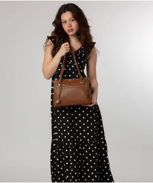 The 'Teresa' handbag style from NiNa Amora is crafted from natural leather with a soft to the touch pebble grain finish that elevates this classic design. A unique dual zipped compartments adorn this bag and are lined and offer ample space for all your essentials thanks to the zipped and slip pocket in each main compartment. Additional storage space is provided by a zipped pocket on the front of the bag which is ideal for secure on-the-go storage. Dual leather handles adorn this style with a drop length of 25cm. Silver metal fittings and zips give this design a elegant look alongside the exquiste NiNa Amora X logo which is embossed in silver foil on the front and hanging charm for a luxurious finishing touch.