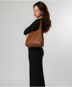 As part of the Nina Amora range, the 'Celeste' handbag is inspired by our designer's daughter and all about elevating classic designs through high quality natural leather with a pebble grain finish. A unique trio of compartments provide ample space for all your essentials with the central  compartment being secured with a zip over top. On either side you will find slip sections, perfect for on-the-go storage.  Additional storage space is provided by a internal zipped pocket - perfect for your phone and keys. Dual leather handles adorn the 'Celeste' with a drop lenght of 25cm. Metal fittings and zips give this design an elegant look which alongside the NiNa Amora X logo embossed on the front and hanging charm adding a luxurious finishing touch.